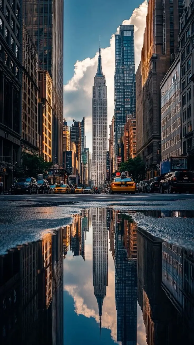 a city street with tall buildings reflecting in the water
