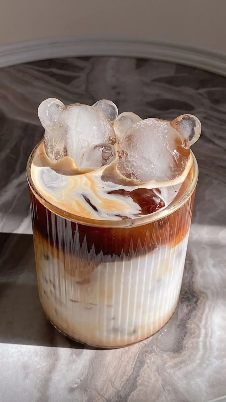 an iced drink with ice cubes in it on a marble table top, ready to be served