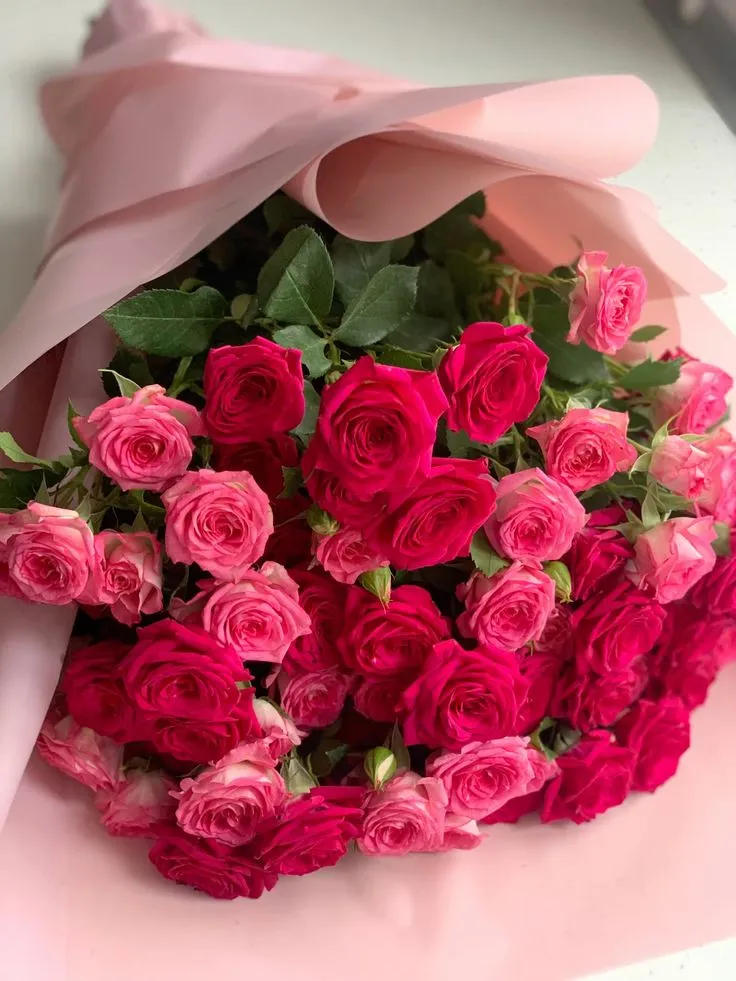 a bouquet of pink roses is wrapped in paper and ready to be placed on the table