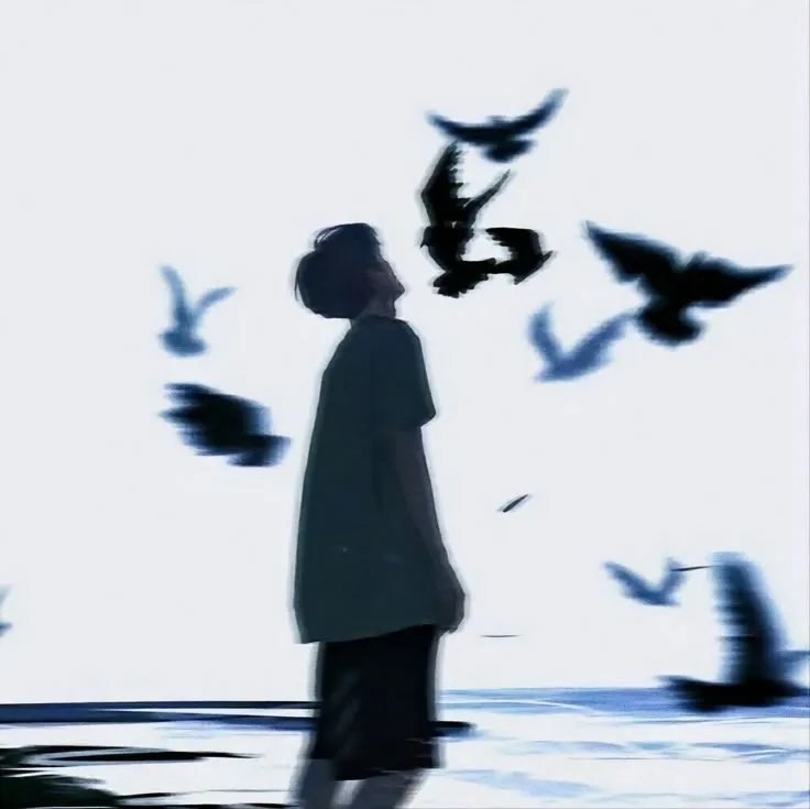 a blurry image of a person standing in front of birds flying over the water