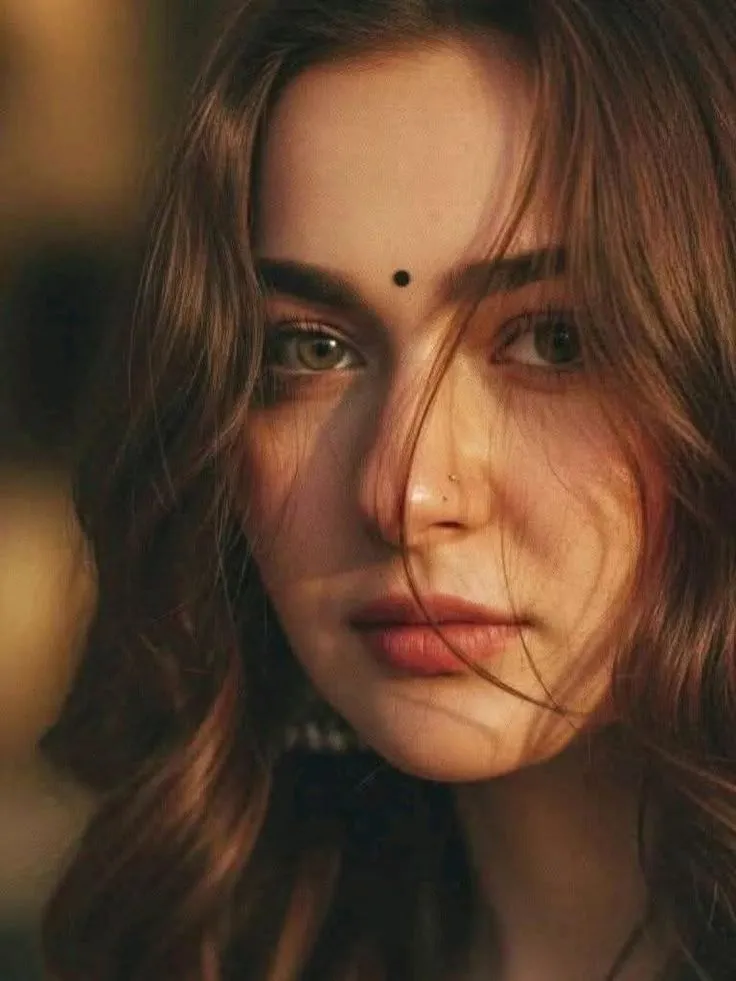 a woman with long hair and piercings on her forehead is looking at the camera