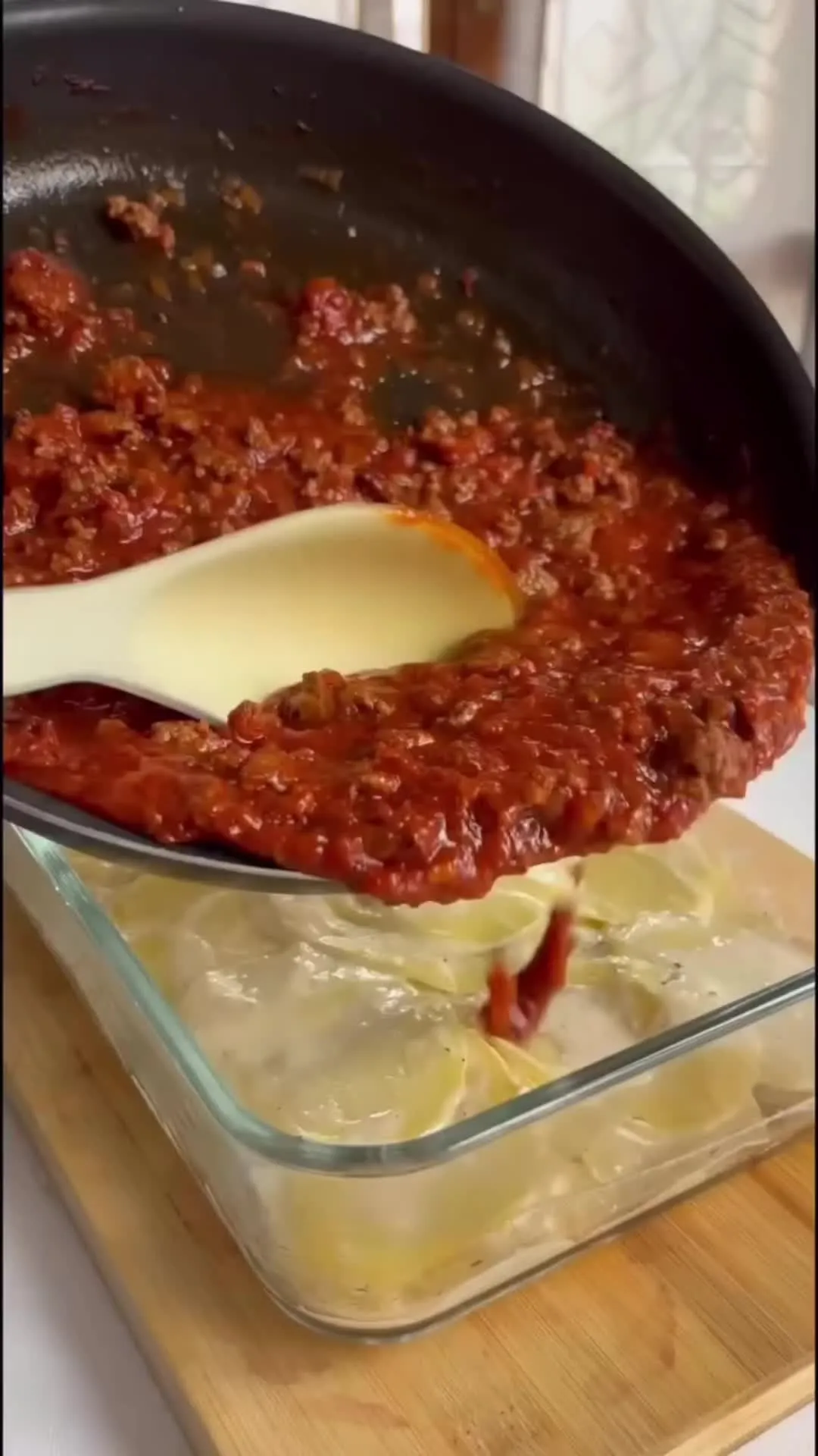 someone is cutting into some lasagna casserole in a glass baking dish