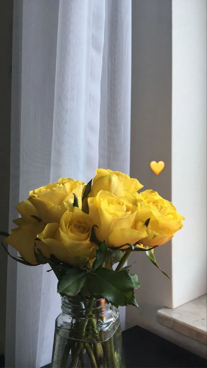 yellow roses in a glass vase on a table