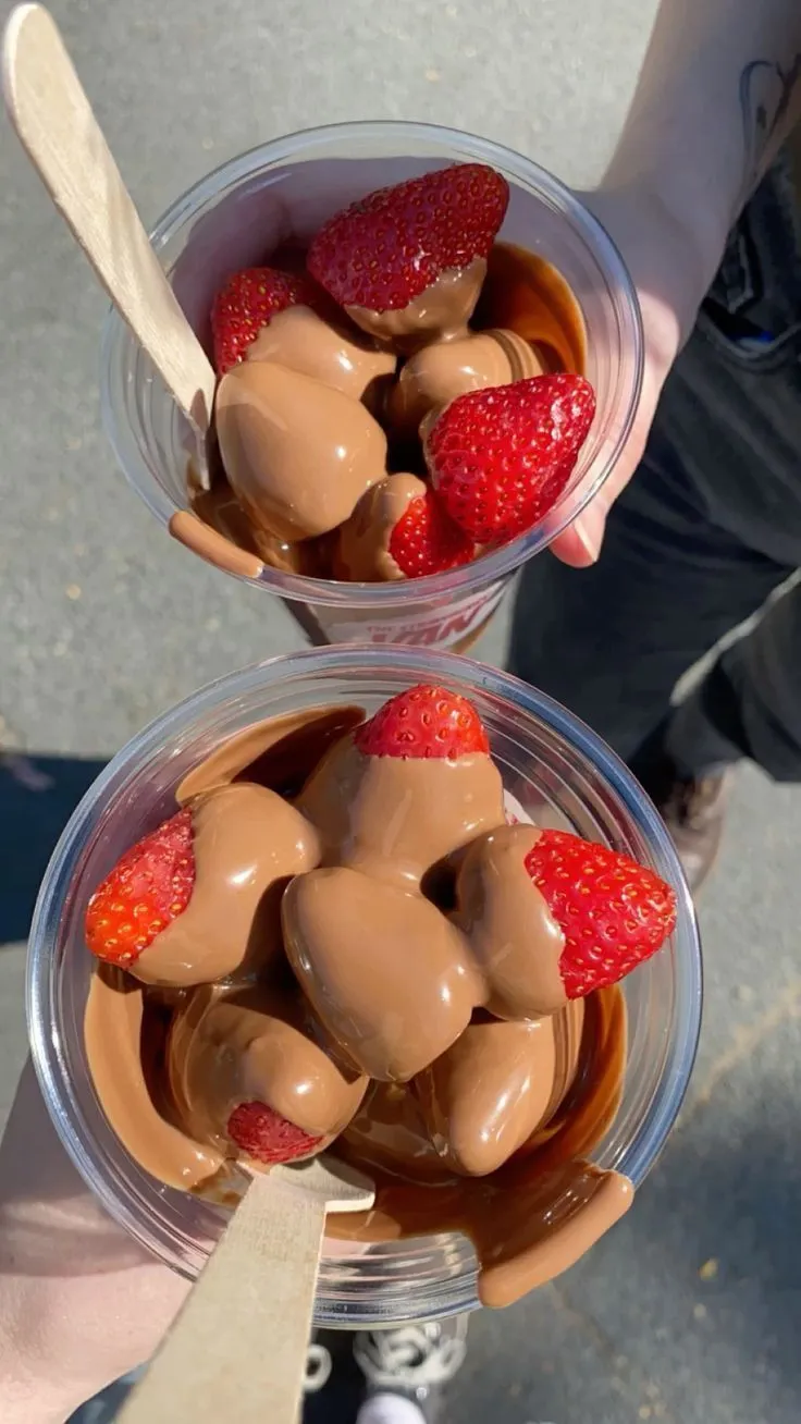 two bowls filled with chocolate and strawberries on top of each other next to a person's hand