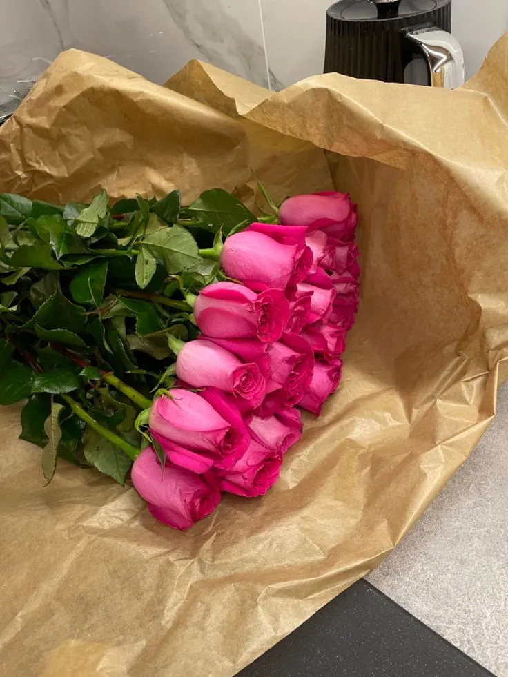 a bunch of pink roses sitting on top of a brown paper bag