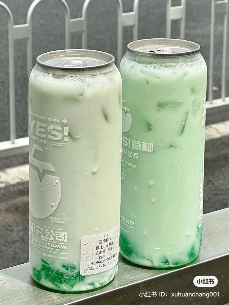 two cans of soda sitting next to each other on a ledge near a fence and railing