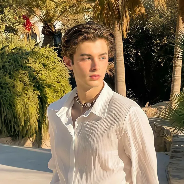 a young man standing in front of palm trees
