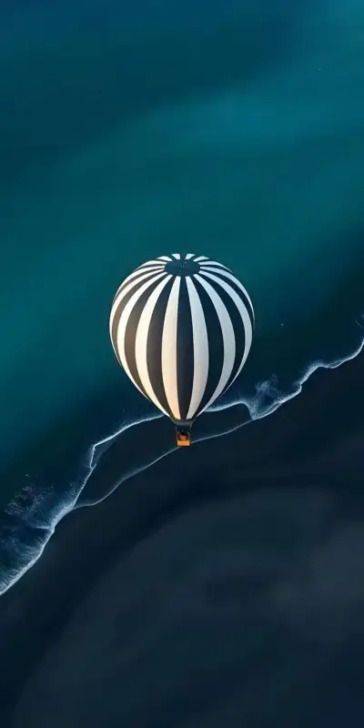 an aerial view of a hot air balloon floating in the ocean water with waves around it