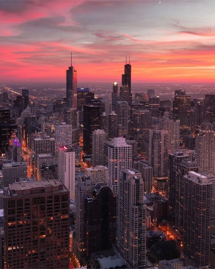 the city skyline is lit up at night, with skyscrapers in the foreground