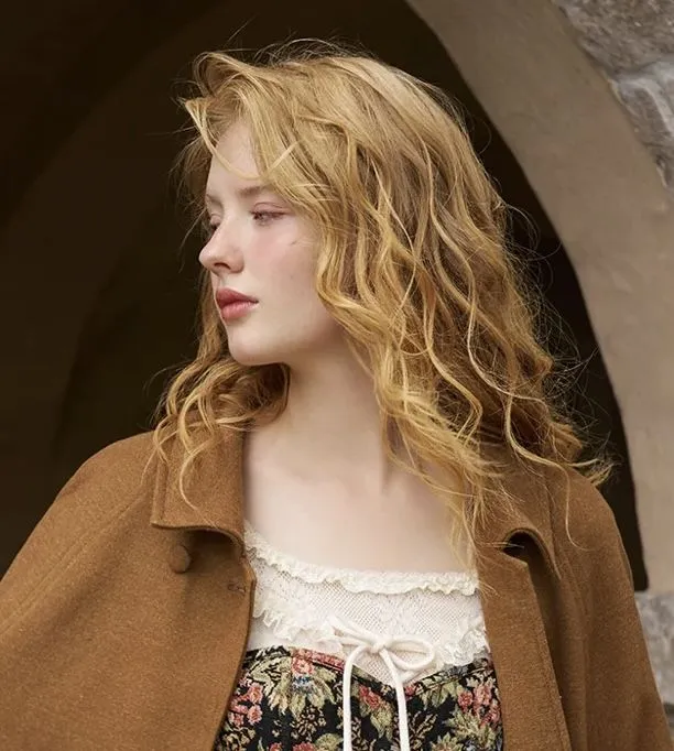 a woman with blonde hair wearing a brown coat