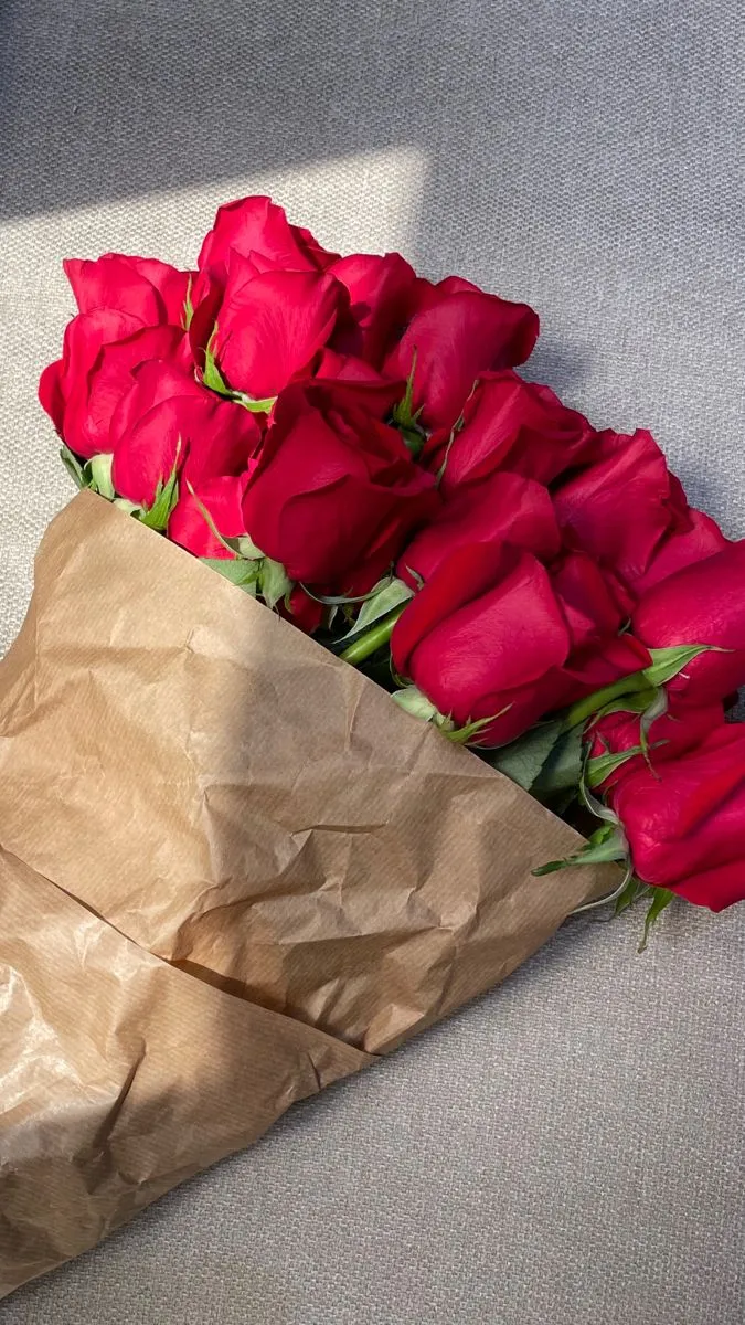 a bunch of red roses in a brown paper bag