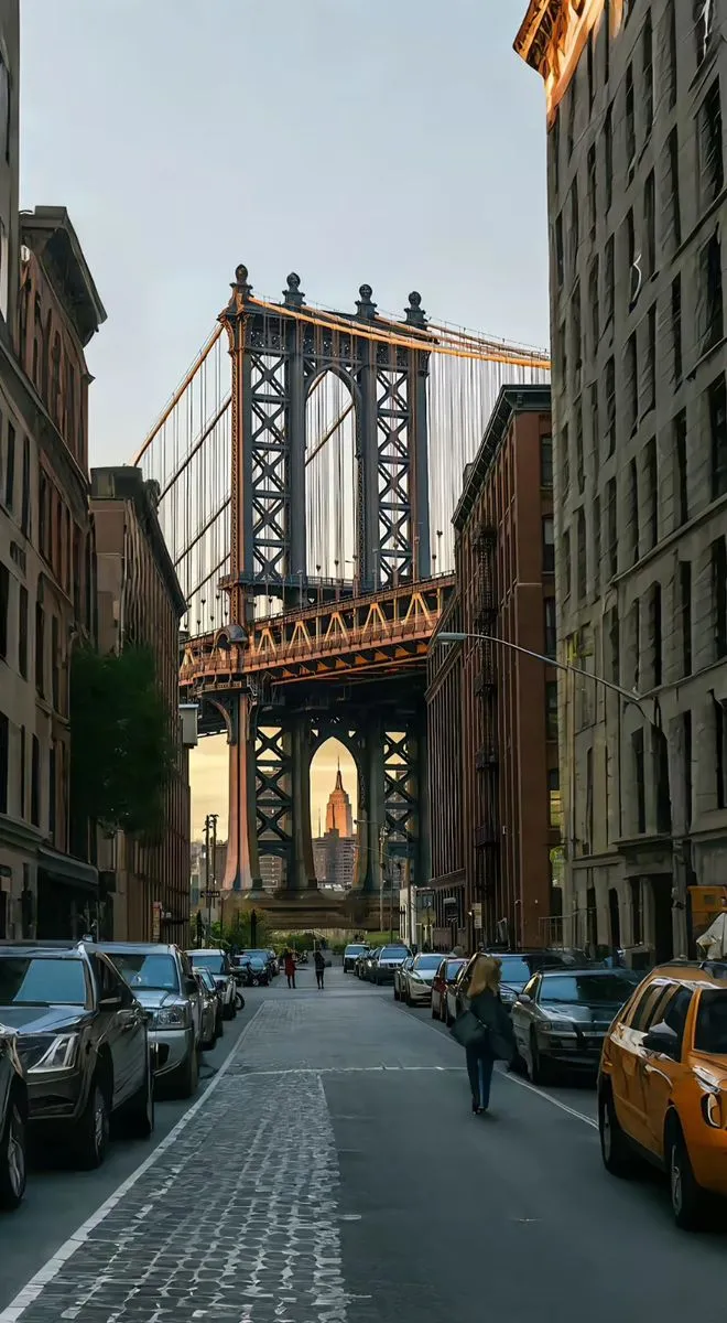 cars are parked on the street in front of tall buildings and a bridge over it