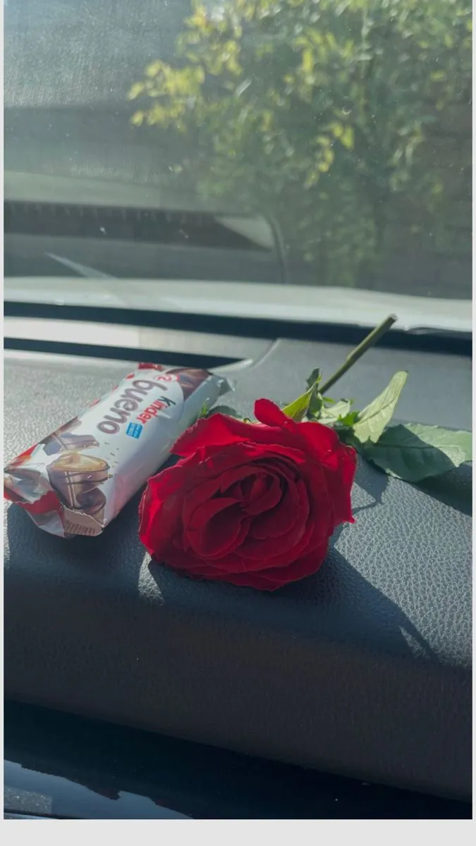 a red rose sitting on top of a window sill next to a tube of toothpaste