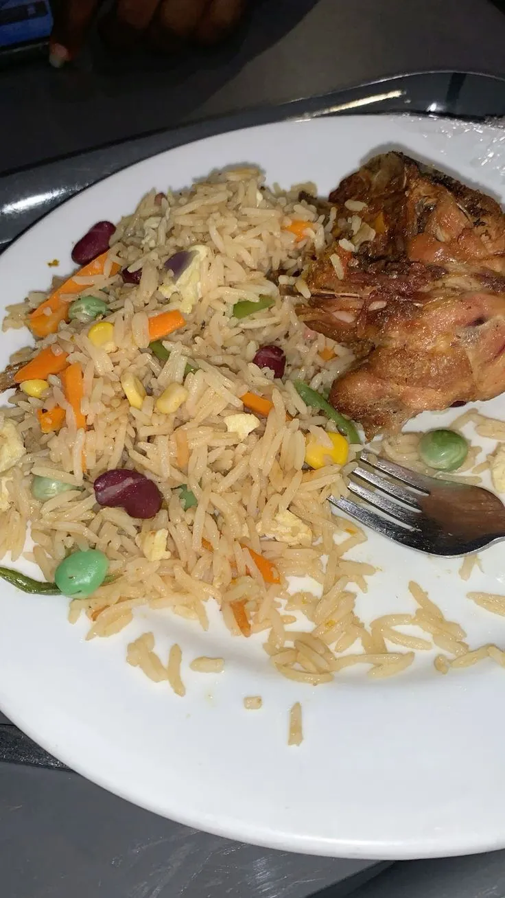 a white plate topped with rice, meat and veggies next to a fork