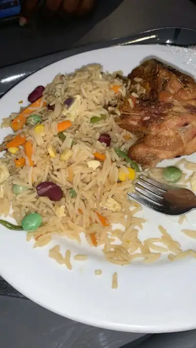 a white plate topped with rice, meat and veggies next to a fork