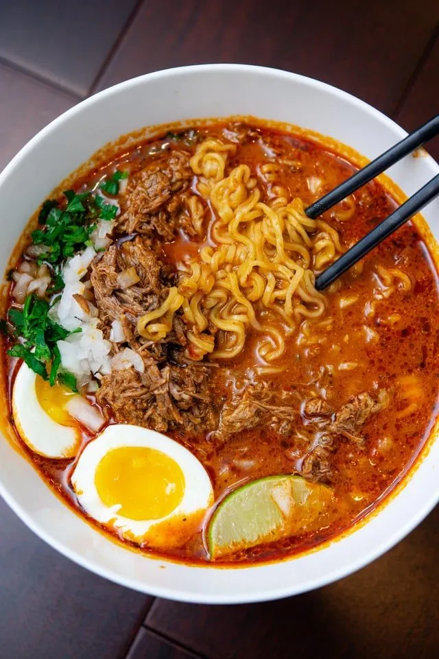 a bowl filled with noodles, meat and eggs