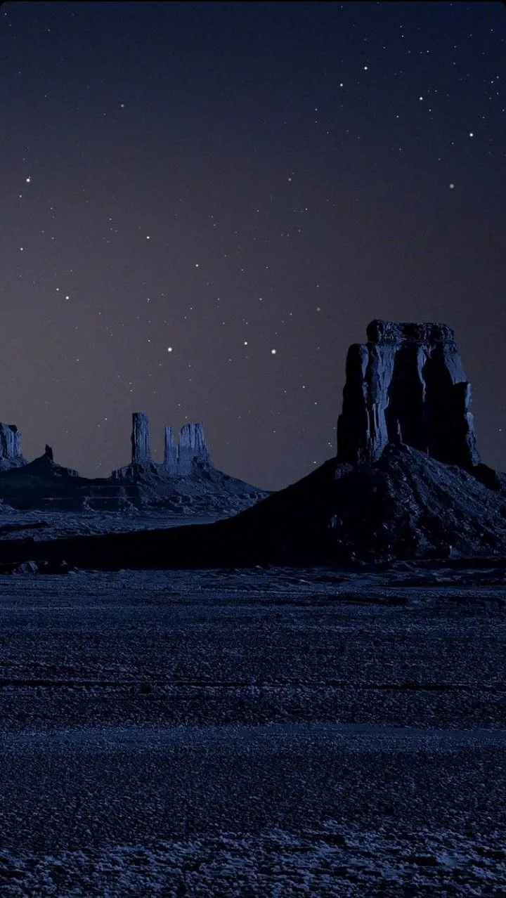 the night sky is lit up with stars above some mountains and desert land, as seen from across the water