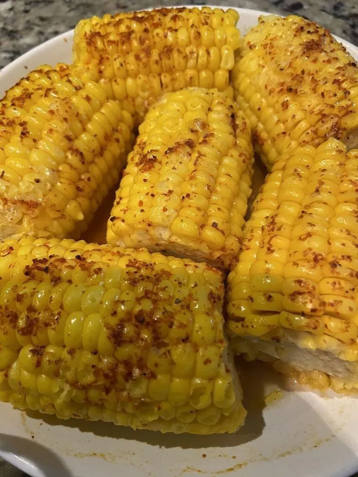 grilled corn on the cob served on a white plate