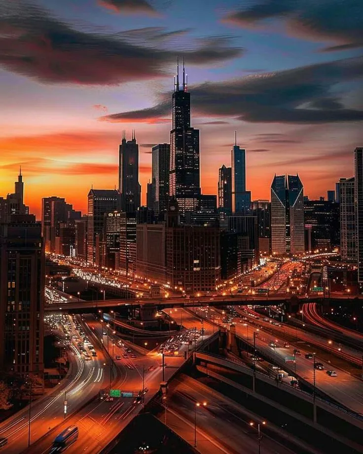 the city skyline is lit up at night, with cars driving on the road below