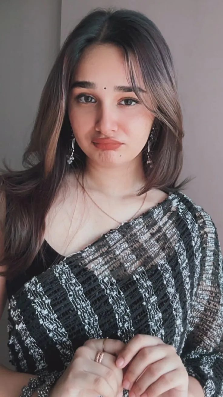 a woman in a black and white top is holding her hands together while looking at the camera