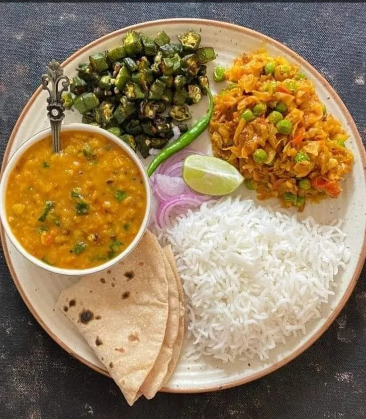 a white plate topped with rice and vegetables next to a bowl of beans, tortilla