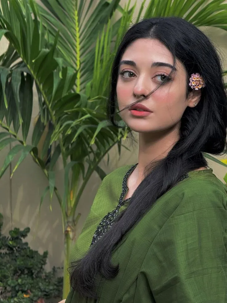 a woman with long black hair wearing a green dress