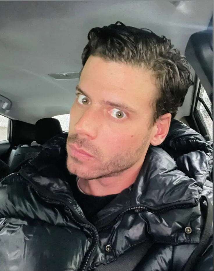 a man sitting in a car looking at the camera with an emoticive message above his head