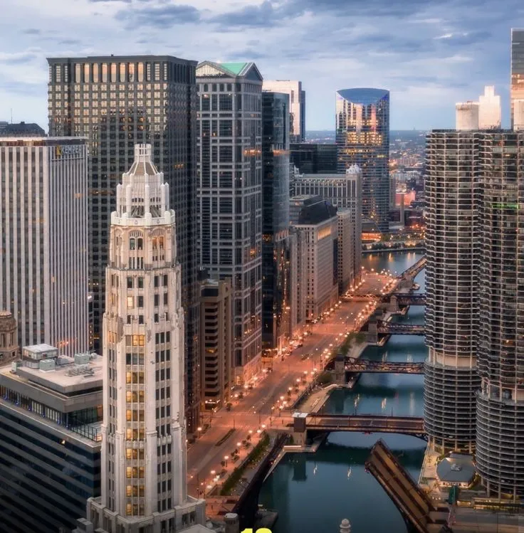 an aerial view of a city with skyscrapers and water in the foreground at dusk
