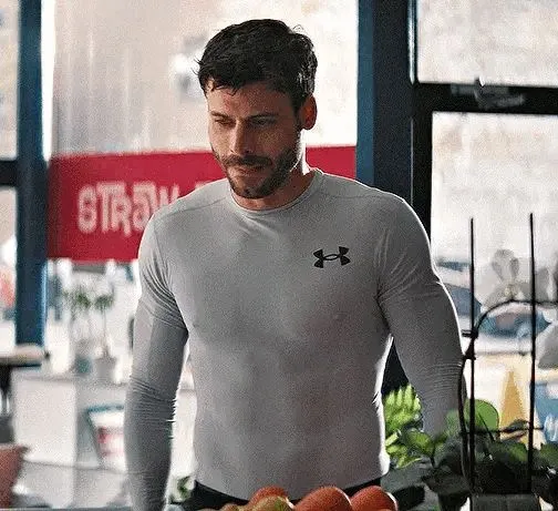 a man standing in front of a table filled with apples and oranges on it