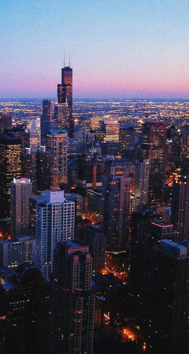 an aerial view of the city at night time with skyscrapers in the foreground