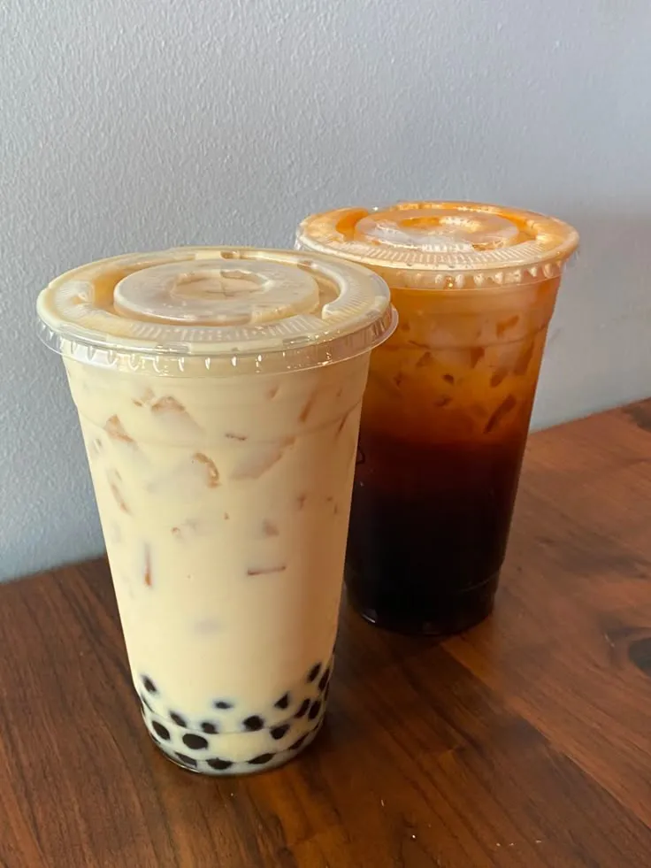 two iced drinks sitting on top of a wooden table