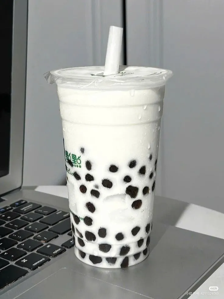 a drink sitting on top of a laptop computer next to a cup with a straw in it