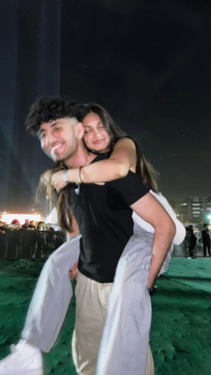 two people standing in the grass with their arms around each other