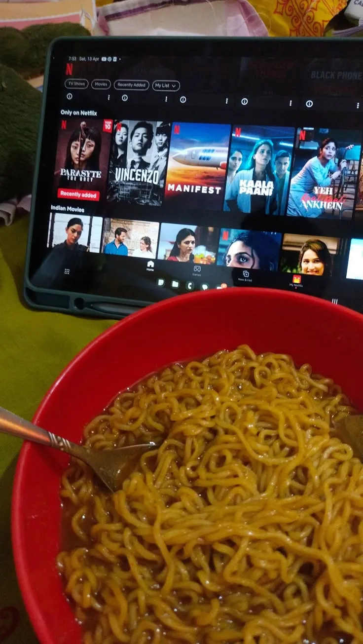a red bowl filled with noodles next to a laptop