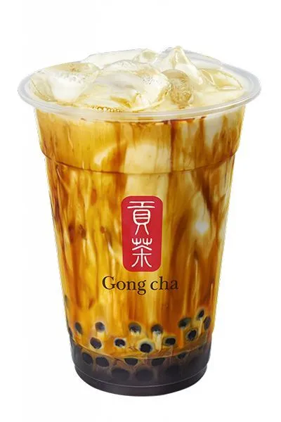 a plastic cup filled with ice cream on top of a white table next to a red sign that says gong cha