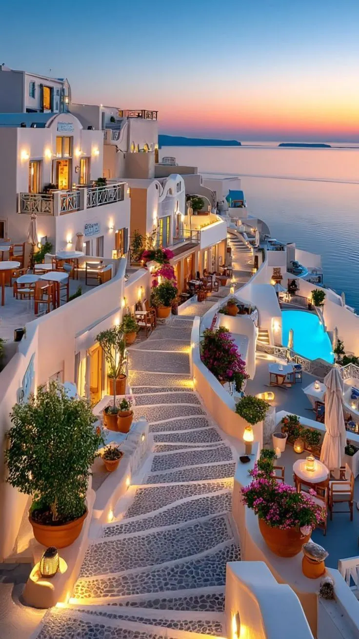 an outdoor restaurant with tables and chairs next to the ocean at night, lit up by candles