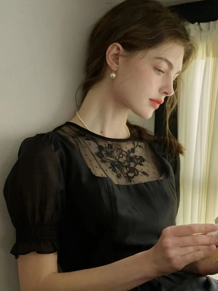 a woman in a black dress is looking at her cell phone while sitting on a window sill