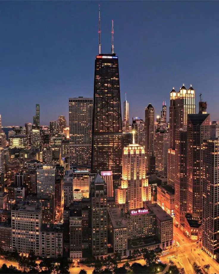 the city skyline is lit up at night with skyscrapers in the foreground and other tall buildings